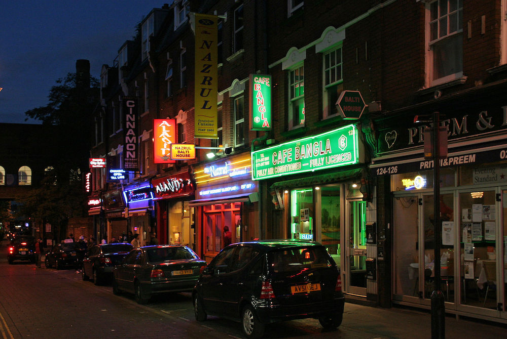 Curry restaurants on Brick Lane in London. Photo Credit: © ahisgett via Wikimedia Commons.